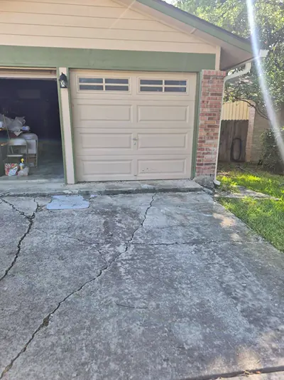 The same driveway after removal, with the junk gone and only the cracked concrete in front of the garage door