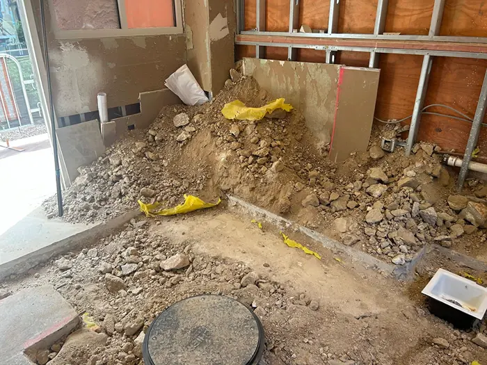 Piles of dirt, rocks, and broken concrete covering the floor of a construction area before cleanup